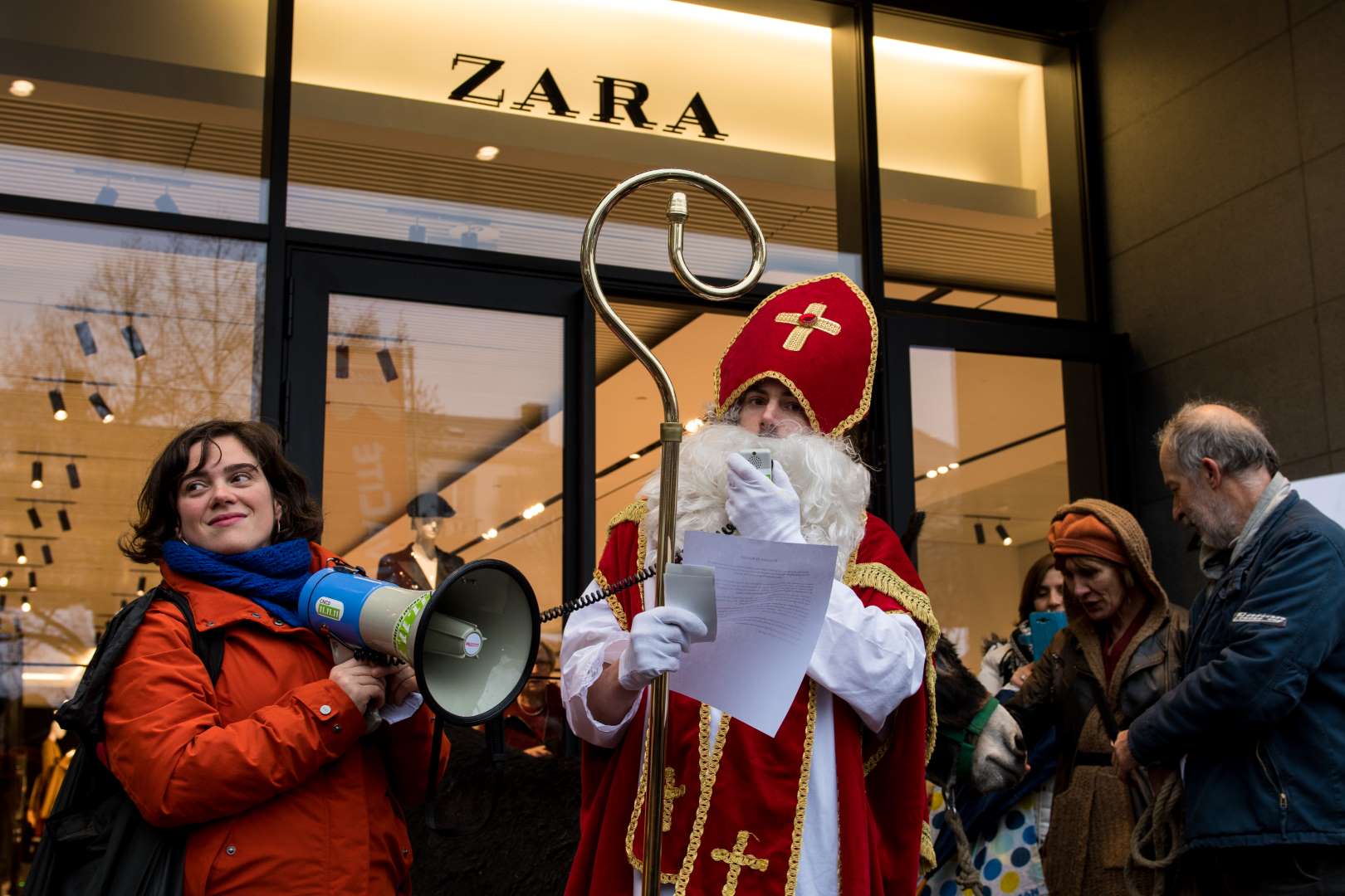 Une femme avec un gueulophone et Saint Nicolas devant Zara à Liège pour plus de justice fiscale