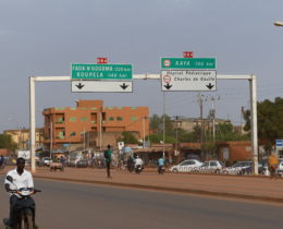 Un homme burkinabé roulant à mobylette sur une autoroute à Ouagadougou. Panneaux de circulation